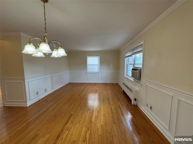 unfurnished dining area featuring a notable chandelier, crown molding, hardwood / wood-style flooring, radiator, and cooling unit