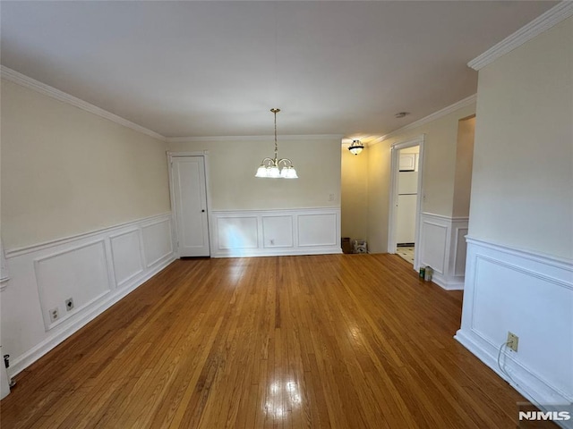 unfurnished dining area with hardwood / wood-style flooring, ornamental molding, and a chandelier