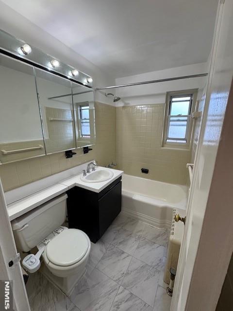 full bathroom featuring toilet, decorative backsplash, tiled shower / bath combo, and vanity