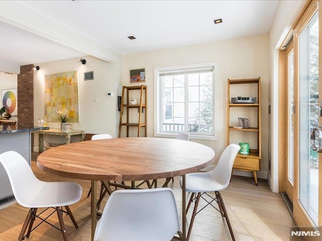 dining area with beam ceiling and light hardwood / wood-style flooring