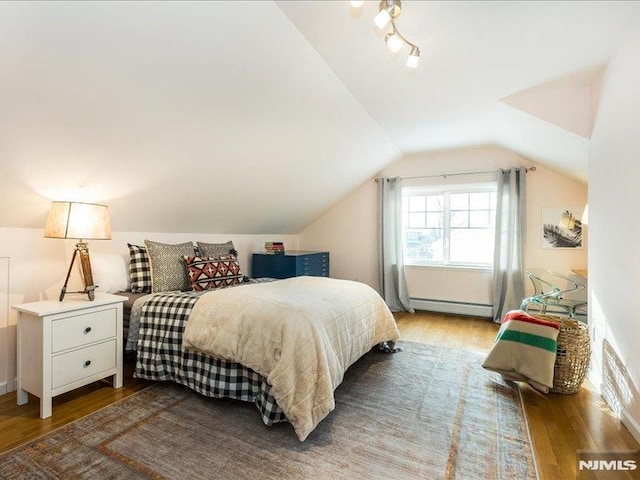 bedroom featuring baseboard heating, lofted ceiling, and hardwood / wood-style flooring