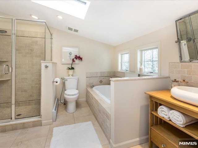 full bathroom featuring toilet, separate shower and tub, tile patterned flooring, vaulted ceiling with skylight, and vanity