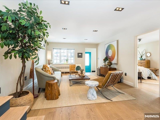 living area featuring radiator heating unit and light hardwood / wood-style flooring