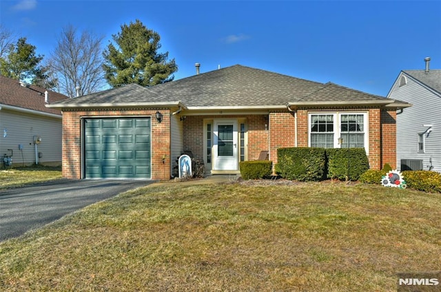 view of front of property with a front yard, central AC unit, and a garage