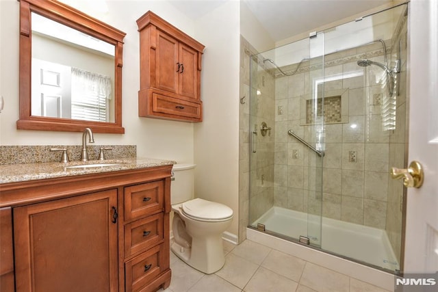 bathroom with toilet, tile patterned flooring, an enclosed shower, and vanity