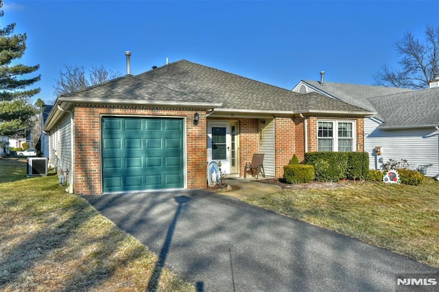 view of front facade with a garage, a front yard, and central AC unit