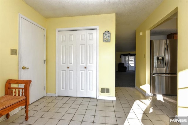 interior space with a textured ceiling and light tile patterned floors