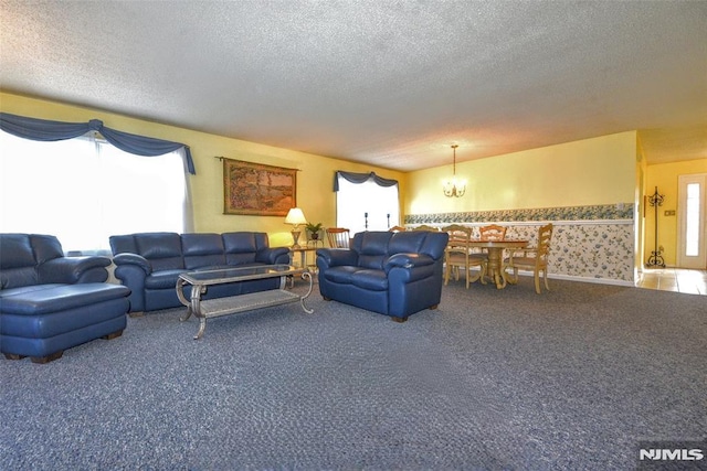 living room featuring a textured ceiling, carpet, and an inviting chandelier