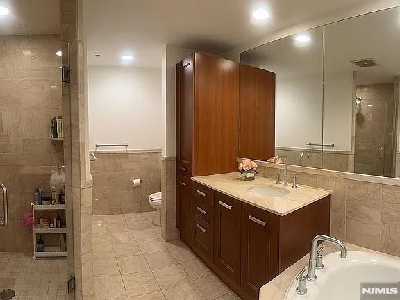 full bathroom featuring toilet, tile patterned flooring, tile walls, shower with separate bathtub, and vanity