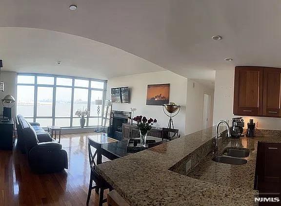 kitchen featuring sink, light stone counters, floor to ceiling windows, and hardwood / wood-style flooring