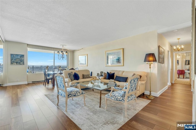 living room featuring a chandelier, a textured ceiling, and light hardwood / wood-style flooring