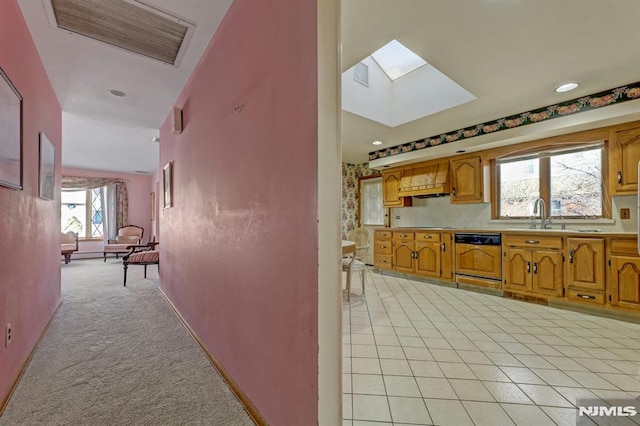 kitchen featuring light carpet, a skylight, sink, and paneled dishwasher