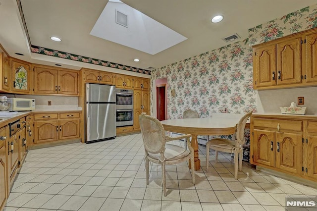 kitchen featuring light tile patterned floors, appliances with stainless steel finishes, and a skylight