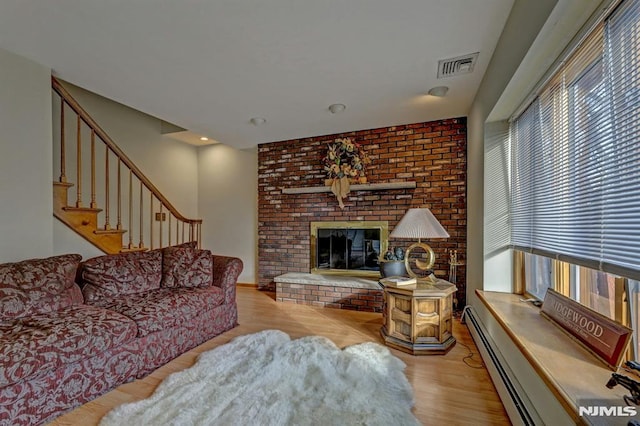 living room with baseboard heating, light hardwood / wood-style flooring, and a fireplace