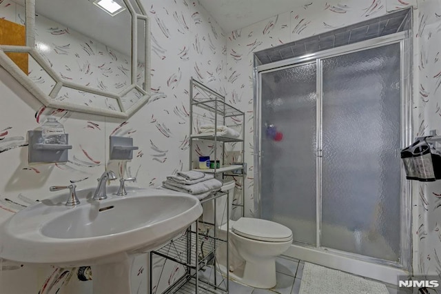 bathroom featuring toilet, tile patterned floors, walk in shower, and sink