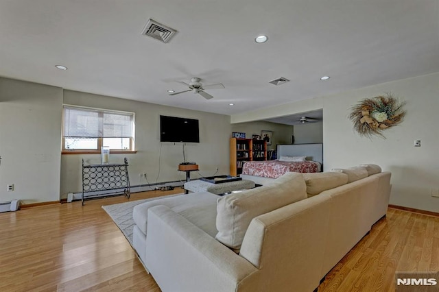 living room featuring ceiling fan, baseboard heating, and light hardwood / wood-style flooring