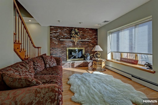 living room with a brick fireplace, light hardwood / wood-style flooring, and a baseboard radiator