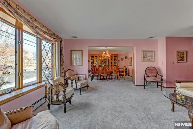 living room featuring light colored carpet, a baseboard heating unit, and a chandelier