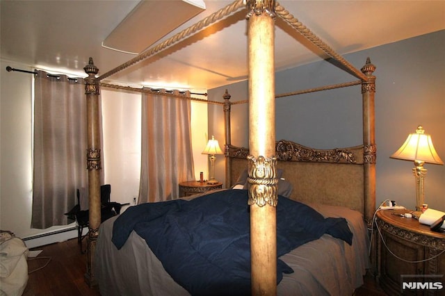 bedroom featuring wood-type flooring and a baseboard heating unit