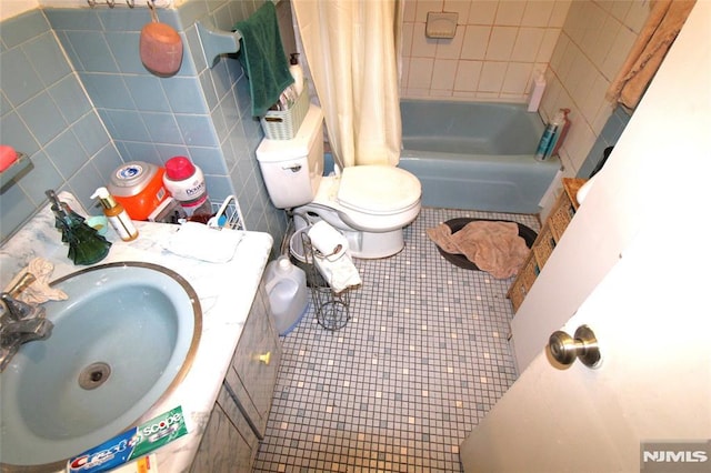 full bathroom with tile walls, shower / bath combination with curtain, tile patterned flooring, vanity, and toilet