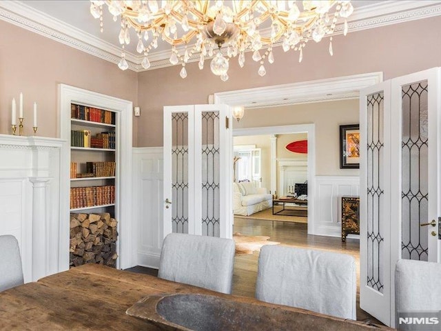 dining area with built in shelves, ornamental molding, and a chandelier