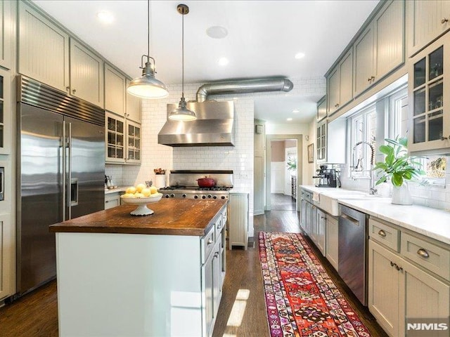 kitchen featuring wall chimney range hood, appliances with stainless steel finishes, gray cabinetry, and a kitchen island