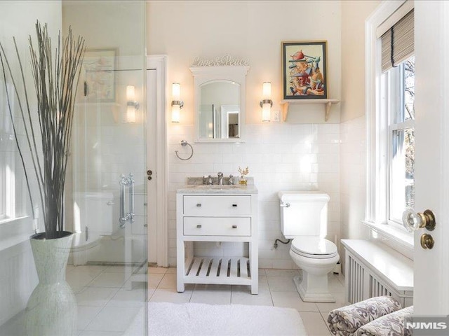 bathroom with a shower with shower door, tile walls, tile patterned floors, and toilet