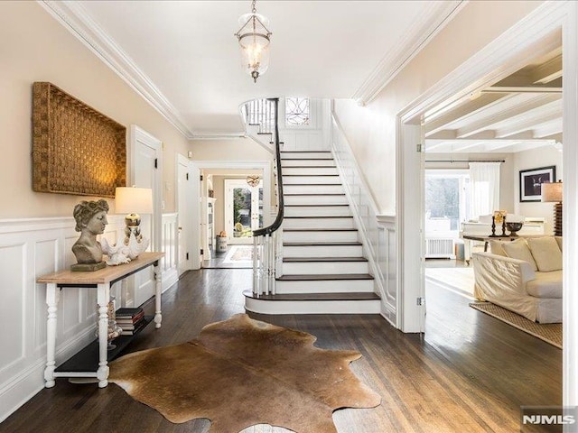 stairway with hardwood / wood-style flooring, plenty of natural light, radiator heating unit, and crown molding