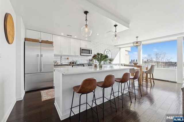 kitchen with a kitchen island, white cabinets, a kitchen breakfast bar, hanging light fixtures, and stainless steel appliances