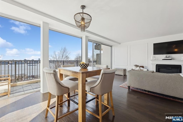 dining area with a water view, dark wood-type flooring, and a wall of windows