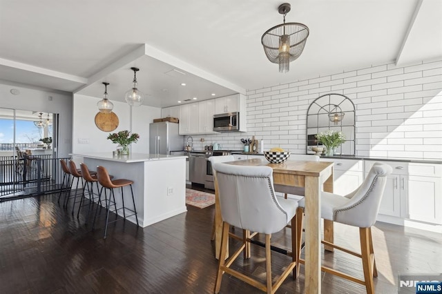 kitchen with appliances with stainless steel finishes, a center island, decorative backsplash, white cabinets, and decorative light fixtures