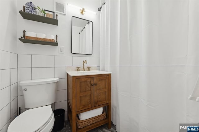 bathroom featuring a shower with curtain, vanity, toilet, and tile walls