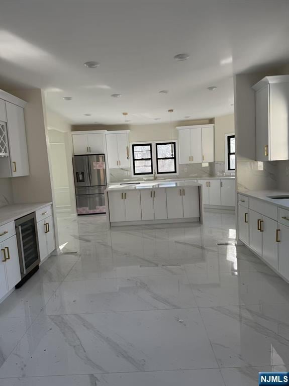 kitchen featuring stainless steel fridge with ice dispenser, wine cooler, sink, backsplash, and white cabinets