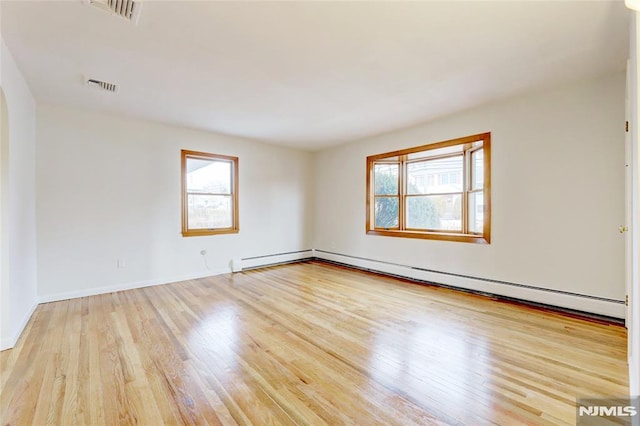 empty room featuring light wood-type flooring and a baseboard heating unit