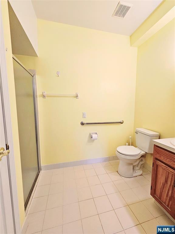 bathroom with toilet, vanity, a shower with door, and tile patterned floors