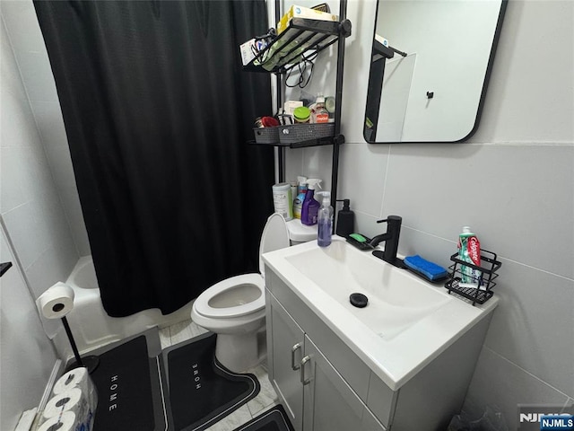 full bathroom featuring toilet, shower / bathtub combination with curtain, tile walls, and vanity