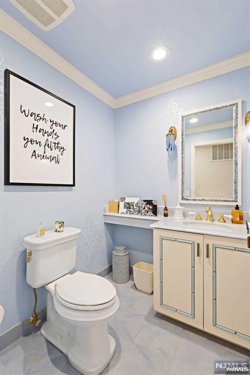 bathroom featuring toilet, ornamental molding, and vanity