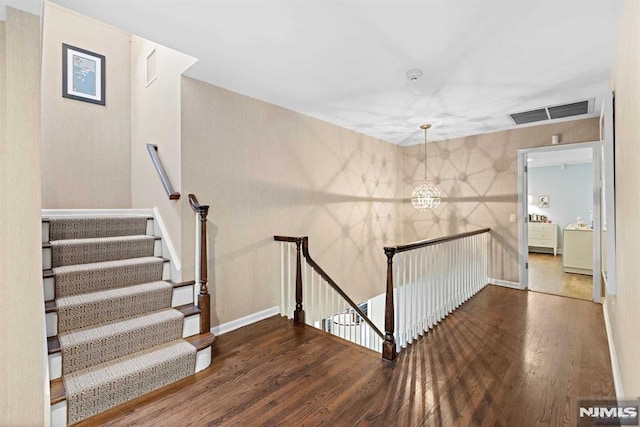 stairs with an inviting chandelier and hardwood / wood-style floors