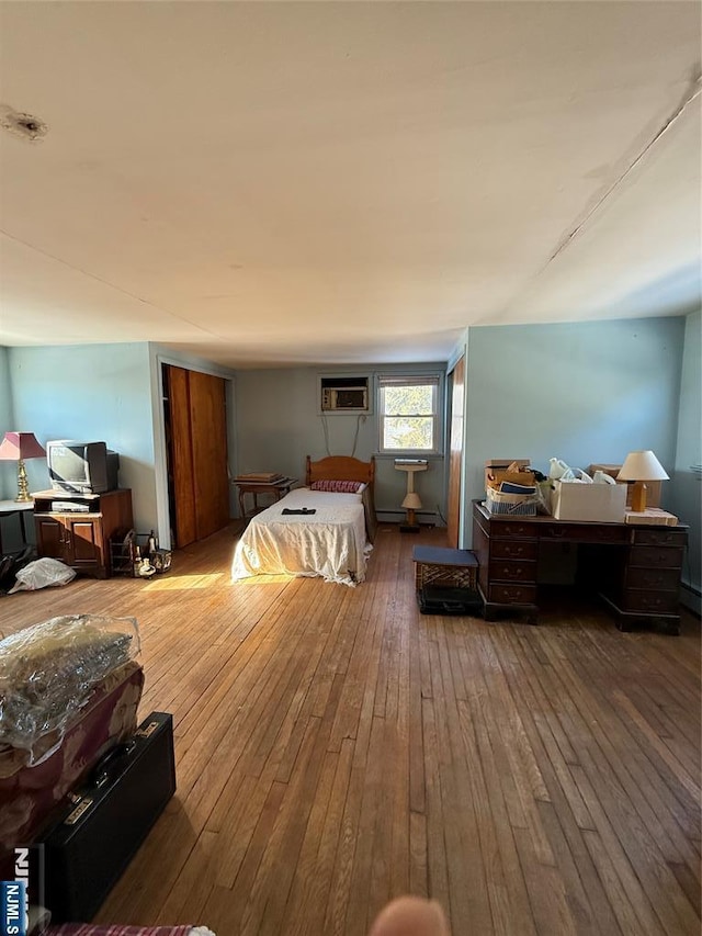 bedroom featuring dark hardwood / wood-style flooring and a wall unit AC