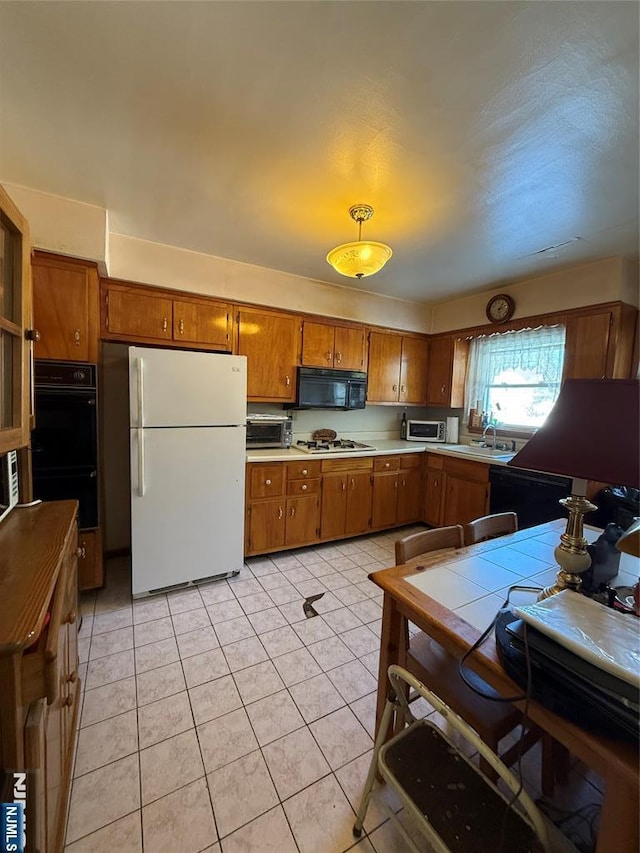 kitchen featuring light tile patterned flooring, tile counters, sink, and black appliances