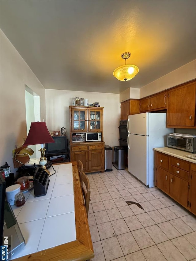 kitchen with pendant lighting, tile countertops, white fridge, and light tile patterned floors