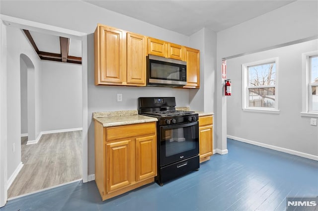 kitchen featuring black gas range oven, dark hardwood / wood-style flooring, and beamed ceiling