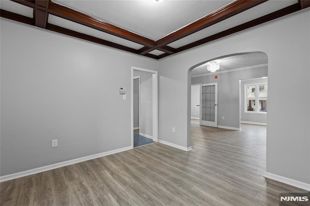 unfurnished room featuring light wood-type flooring, ornamental molding, beam ceiling, and coffered ceiling