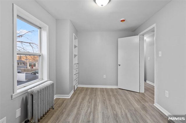 bedroom with light hardwood / wood-style floors and radiator heating unit