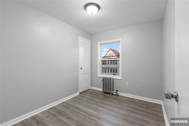 empty room with wood-type flooring and radiator heating unit