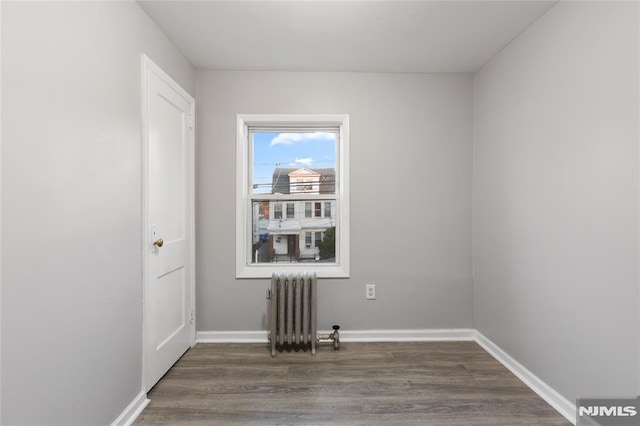 empty room featuring dark hardwood / wood-style flooring and radiator heating unit