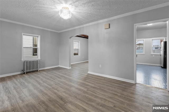 unfurnished room with hardwood / wood-style flooring, a textured ceiling, radiator, and crown molding