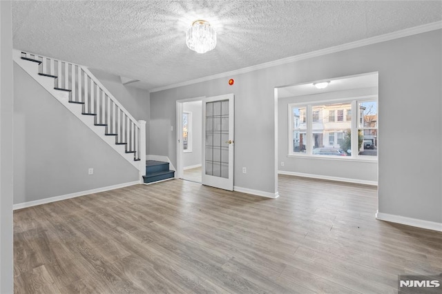 unfurnished living room with hardwood / wood-style flooring, a textured ceiling, ornamental molding, and french doors