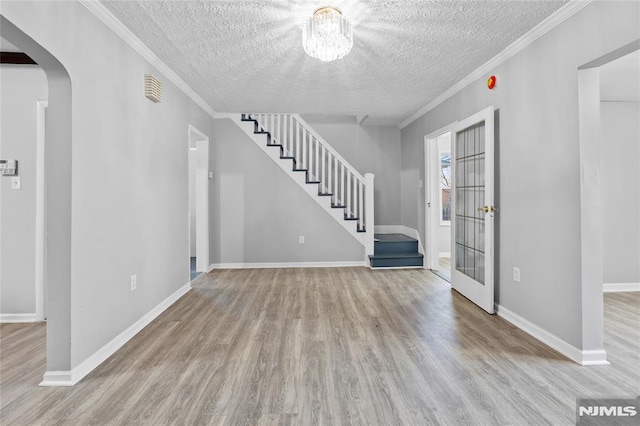 foyer entrance with light hardwood / wood-style floors, a textured ceiling, and crown molding