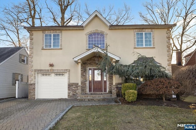 view of front of home featuring stone siding, stucco siding, an attached garage, and decorative driveway